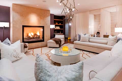 Luxury living room with fireplace, cream sofas, geometric chandelier, and modern furnishings