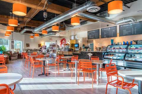 Modern coffee shop interior with orange pendant lights and contemporary seating
