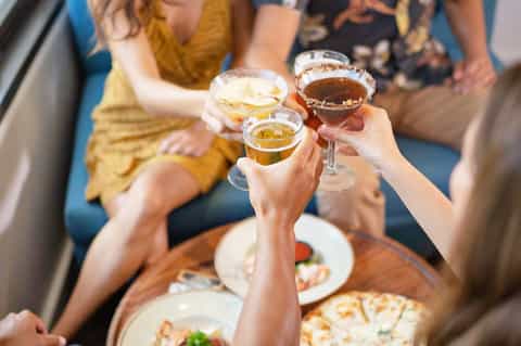 Group of people toasting with cocktails at a social gathering indoors