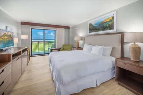 Modern hotel bedroom with ocean view balcony, king bed, and contemporary furnishings