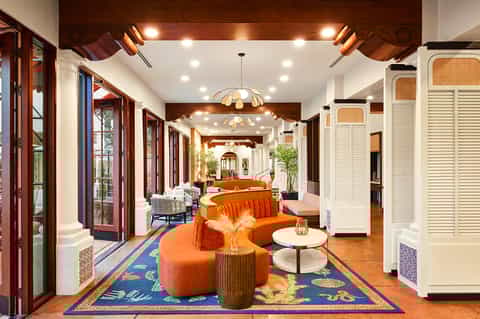 Stylish resort hallway with orange curved seating, wooden accents, and elegant lighting fixtures