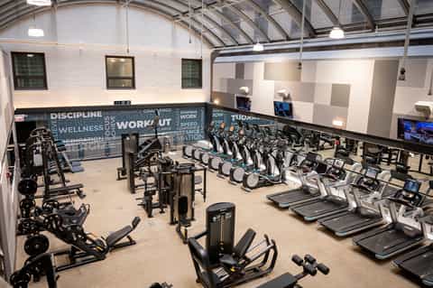 Spacious fitness center with rows of treadmills, exercise bikes, and strength training equipment