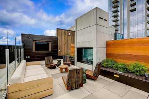 Modern rooftop terrace with contemporary seating, wood accent walls, and city building views