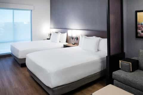 Modern hotel room with dual queen beds and minimalist dark decor