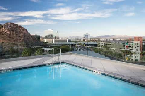 Rooftop pool overlooking downtown cityscape with mountains and urban landscape