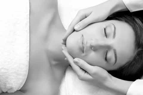 Peaceful spa facial treatment with client relaxing under professional therapist's hands