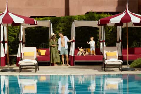 Luxury poolside cabanas with red and white striped umbrellas, family enjoying the resort pool area