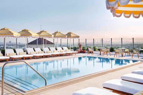 Rooftop pool with yellow and white striped umbrellas overlooking city skyline