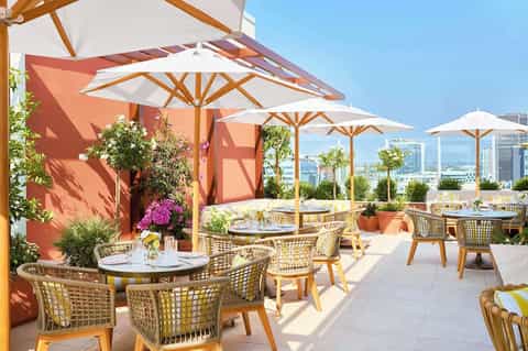 Rooftop terrace with dining tables, umbrellas, and city skyline views