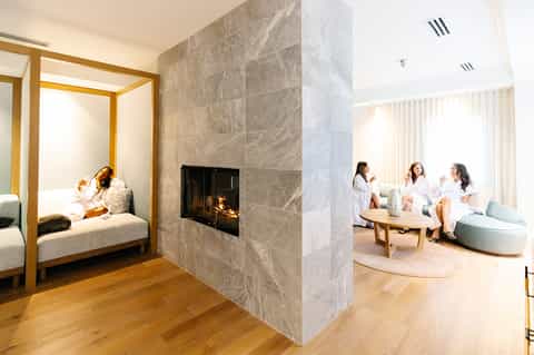 Luxury spa suite with canopy bed, fireplace, and lounge area with guests conversing