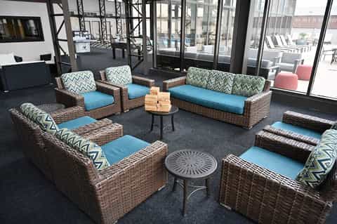Indoor lounge area with wicker furniture, blue cushions, and geometric patterned pillows arranged around small tables