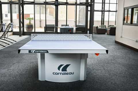 Cornilleau white ping pong table in modern indoor recreation room with floor-to-ceiling windows