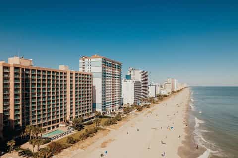 Beachfront resort with multi-story hotel buildings along sandy beach and ocean