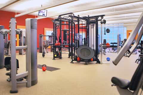 Modern fitness center with multi-functional exercise equipment and large windows overlooking the city