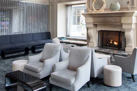 Elegant living room with navy sectional sofa, fireplace with stone mantel, and floor-to-ceiling windows with sheer curtains