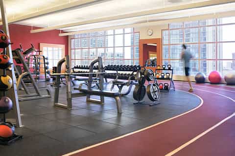 Modern fitness center with exercise equipment, dumbbells, medicine balls, and floor-to-ceiling windows