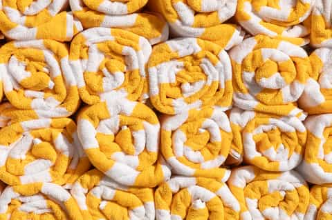 Stack of yellow and white rolled towels displayed closely together