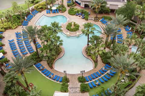 Aerial view of resort pool complex with blue loungers and palm trees
