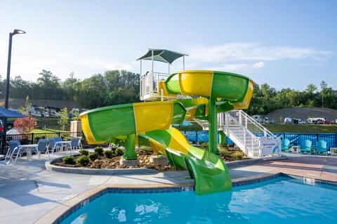 Bright green and yellow water slide twisting above a resort pool with lounge chairs and landscaping