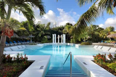 Resort lap pool with white columns, palm trees, and lounge chairs