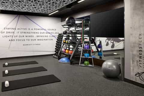 Modern fitness center with dumbbells, kettlebells, exercise mats, and motivational signage