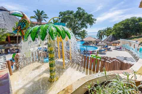 Colorful water park with splash fountain feature, tropical trees, and multiple pools