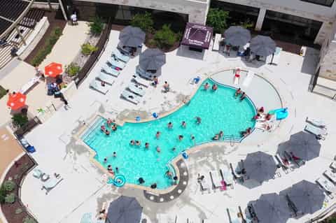 Aerial view of curved resort pool surrounded by loungers and gray umbrellas
