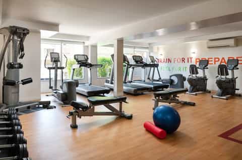 Modern fitness center with cardio equipment, treadmills, weight machines, and exercise accessories on wooden floor