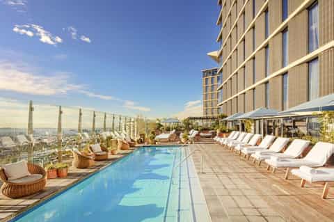 Rooftop infinity pool with city skyline views, lounge chairs, and modern high-rise hotel building