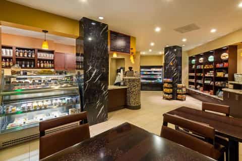 Upscale café interior with black marble pillars, display cases, and yellow accent walls