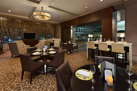 Upscale hotel restaurant and bar with brown tones, dining tables, and lounge seating