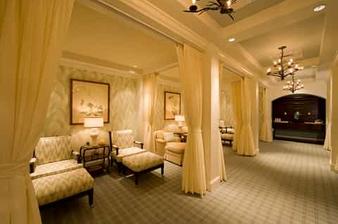 Elegant spa lounge with golden yellow walls, flowing cream curtains, traditional furnishings, and fireplace