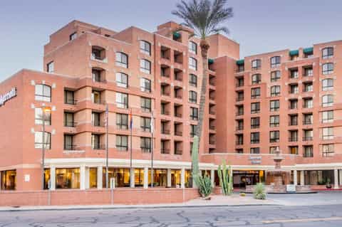 Marriott hotel exterior with red brick facade, multiple stories, ground floor retail, and palm tree