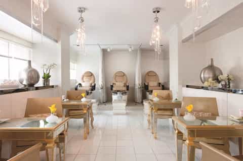 Luxury spa interior with pedicure stations, crystal chandeliers, and neutral tones