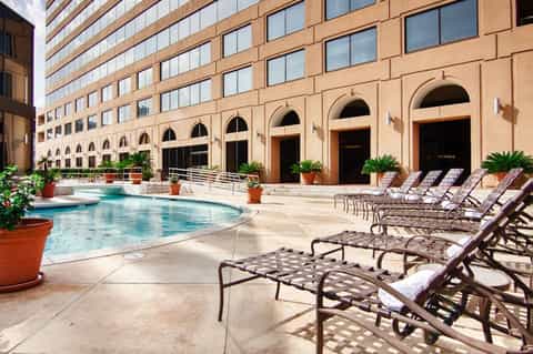 Resort courtyard with arched architecture, lounge chairs, and turquoise pool