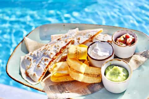 Fish tacos with crispy fries and three dipping sauces served poolside