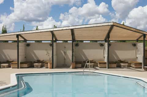 Resort pool with lounge chairs under modern pergola structure and blue sky