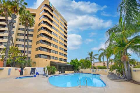 Yellow apartment building with kidney-shaped pool and lounge chairs in courtyard