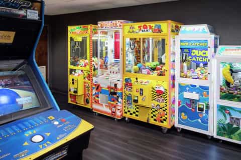 Arcade game room with colorful claw machines and vintage gaming cabinets on dark flooring