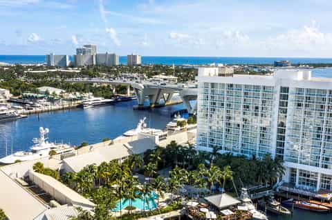 Waterfront resort with white high-rise hotel, marina, pools, and ocean views in tropical setting