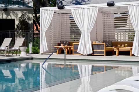 Luxury resort pool with white cabanas, lounge chairs, and high-rise buildings backdrop