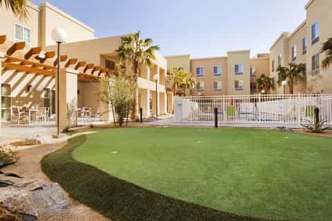 Resort courtyard with putting green, palm trees, pergola seating, and multi-story hotel buildings