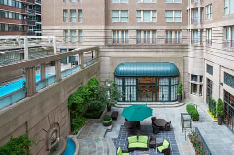 Courtyard terrace with blue umbrella, seating area, and modern building with blue-domed conservatory entrance
