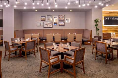 Modern dining area with wooden furniture, purple upholstered booth seating, and framed artwork on walls