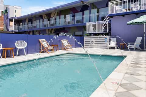 Contemporary pool area with bright blue accent wall, modern furnishings, and residential buildings