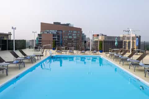 Rooftop infinity pool with blue water overlooking urban cityscape and modern buildings