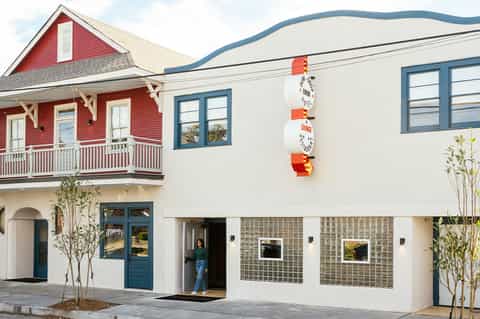 Modern mixed-use building with red cottage-style upper level and white contemporary lower level