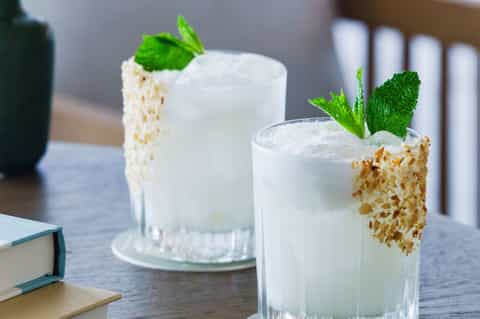 Elegant cocktails with mint garnish and crushed ice rim on wooden table