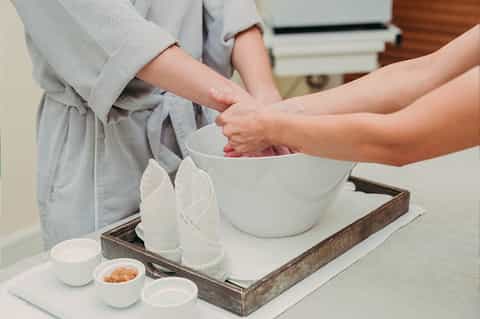 Hands mixing ingredients in white bowl during spa treatment preparation
