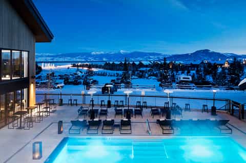 Luxury resort pool deck at dusk overlooking snow-covered mountains and frozen landscape